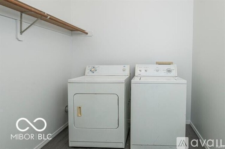 Two white washing machines in a laundry room.