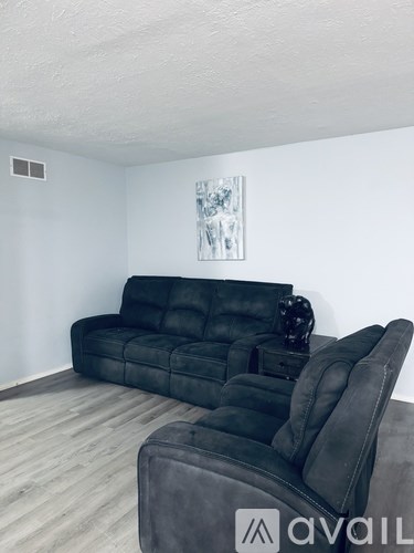 A black leather sofa and ottoman in a room with a painting on the wall.