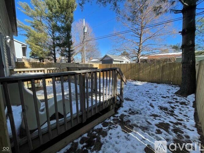 A snow-covered deck with a railing and a view of a residential area.
