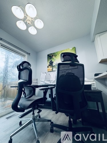 A room with two chairs and a desk with a computer on it.