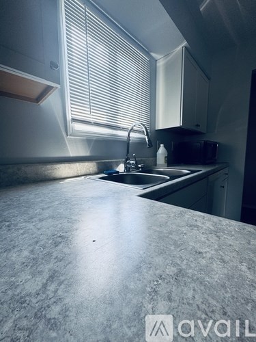 A kitchen with a sink and a window with blinds.