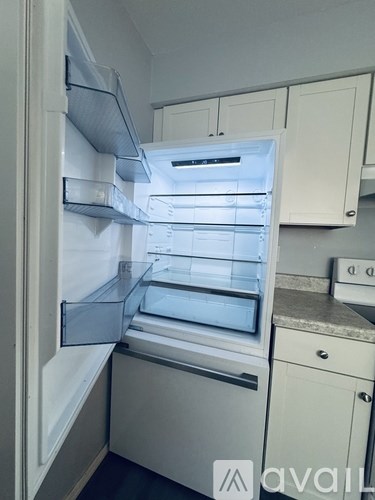 A white refrigerator with its door open and empty.