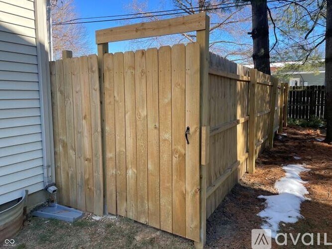 A wooden fence with a gate is in front of a house.
