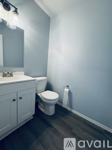 A bathroom with a toilet, sink, and cabinet.