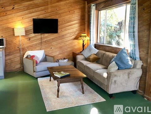 A living room with a couch, a chair, a coffee table, and a television mounted on the wall.