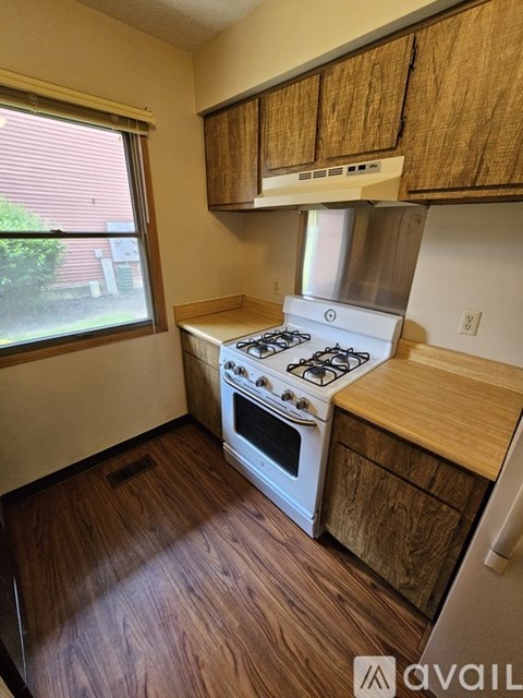 A kitchen with a white stove and wooden cabinets.