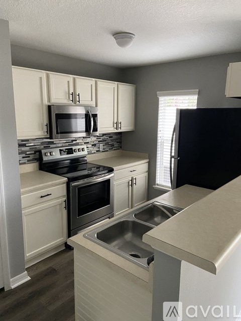 A kitchen with a black refrigerator and stove top oven.