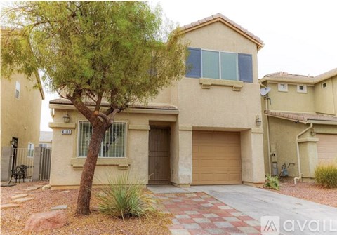 A beige house with a tree in front of it.