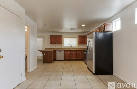 A kitchen with a black refrigerator and wooden cabinets.