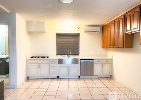A kitchen with white cabinets and a stainless steel sink.