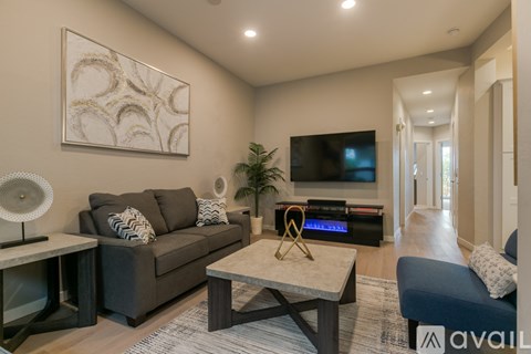 A living room with a grey couch, a coffee table, and a painting on the wall.
