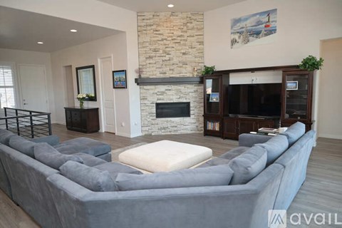 A living room with a grey sectional sofa and a stone fireplace.