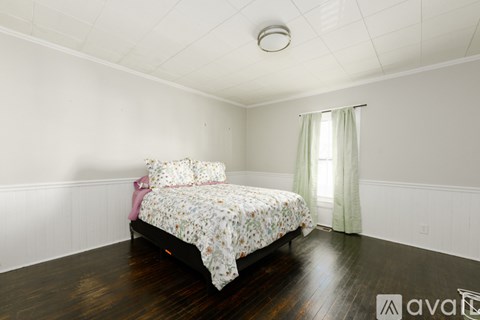 A bedroom with a bed and a window with a green curtain.