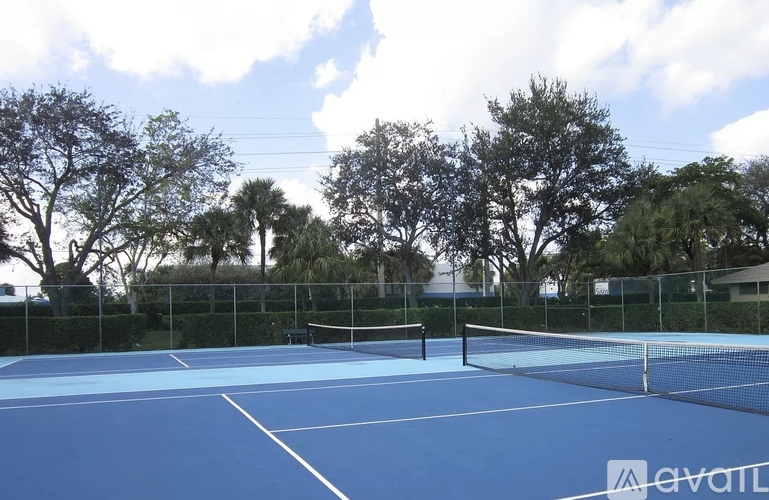 A tennis court with a net and trees in the background.