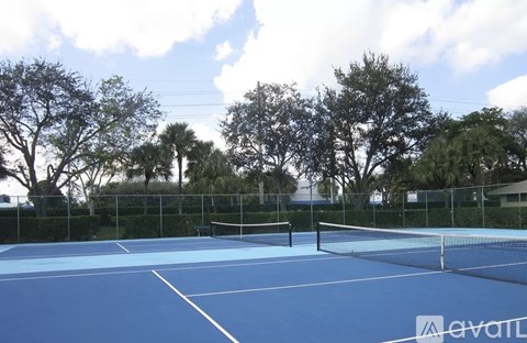 A tennis court with a net and trees in the background.