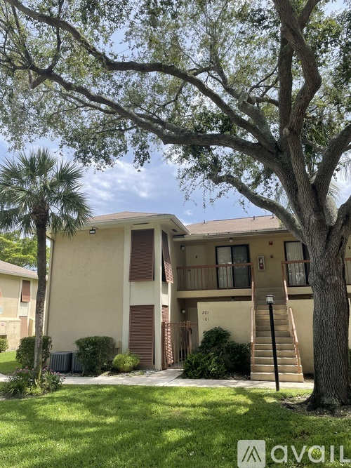 A tree in front of a two-story building with a balcony.