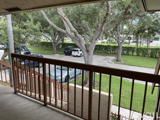 A balcony view of a parking lot with cars and trees.