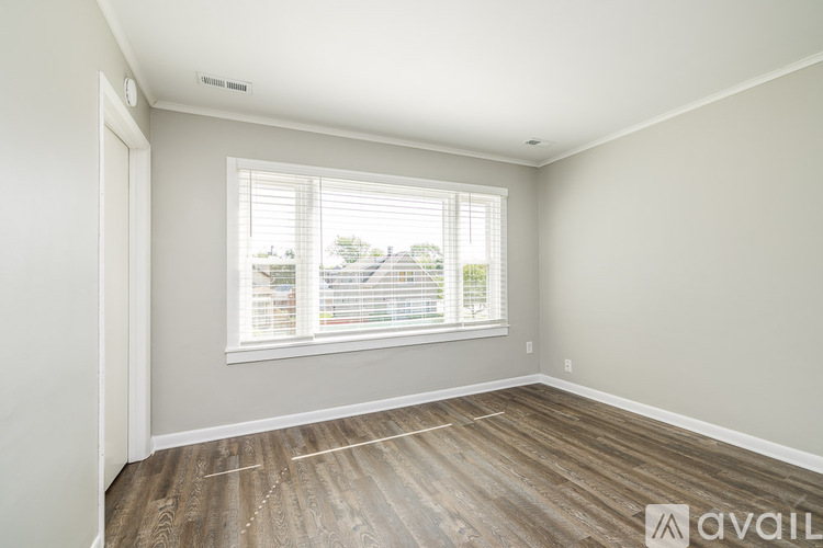 A room with a window and wooden flooring is available for rent.