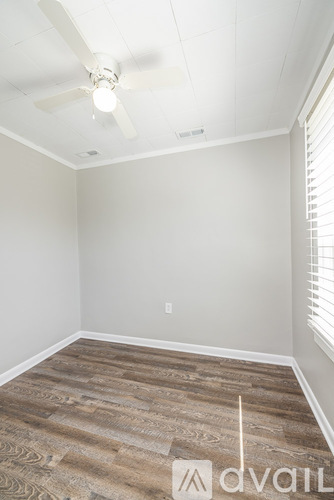 A room with a ceiling fan and wooden flooring.
