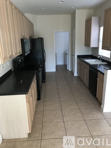 A kitchen with black appliances and wooden cabinets.