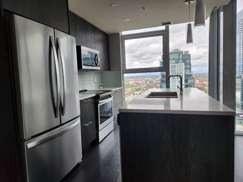 A modern kitchen with stainless steel appliances and a large window overlooking the city.