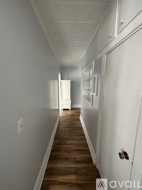 A long hallway with white walls and wood floors.