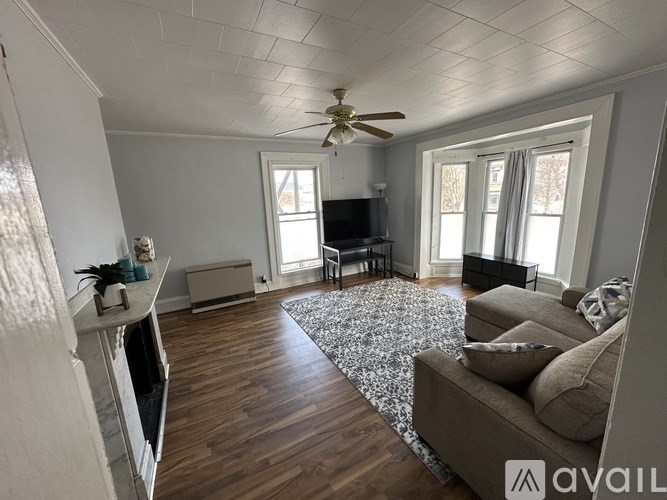 A living room with a brown couch and a ceiling fan.