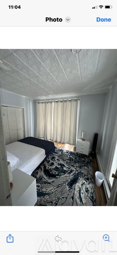 A bedroom with a bed, a dresser, and a window with curtains.