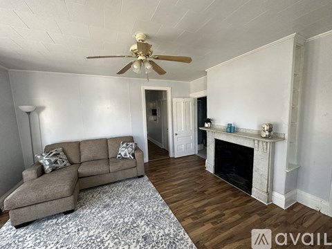 A living room with a grey couch and a fireplace.