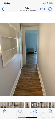 A long hallway with white walls and wooden flooring.