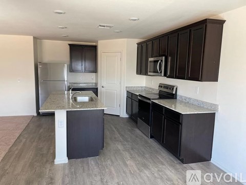 A kitchen with dark brown cabinets and a granite countertop.