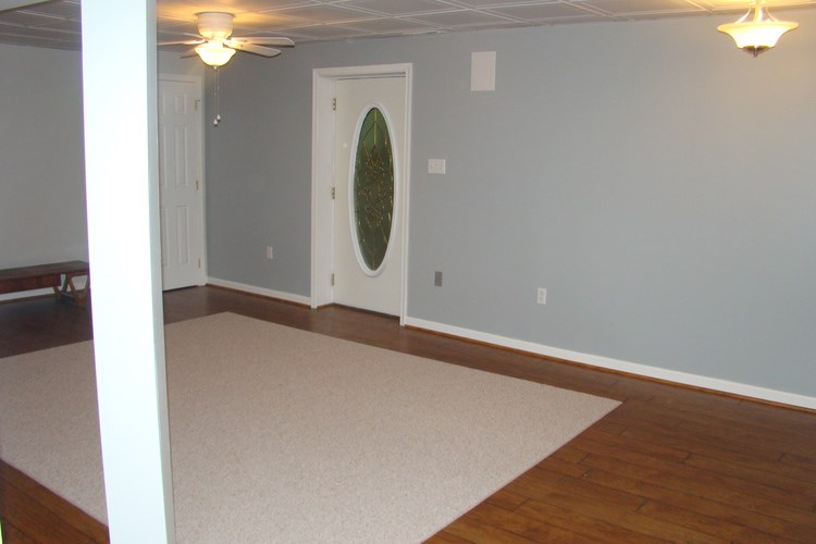 A room with a white rug and a door with a green circle on it.