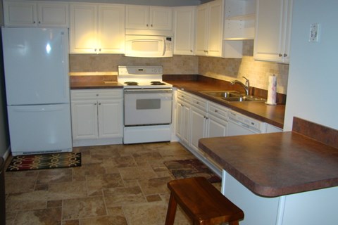A kitchen with white appliances and brown countertops.