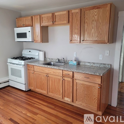 A kitchen with wooden cabinets and a white stove top oven.