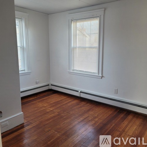 A room with wooden floors and a window with blinds.