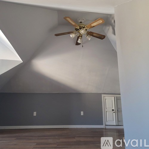 A room with a ceiling fan and a door.