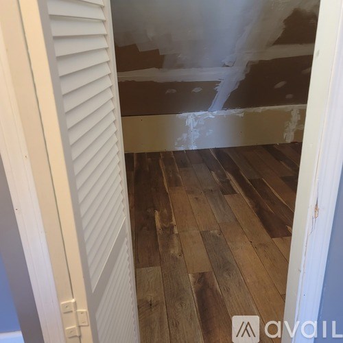 A room with wooden floors and white walls is under renovation.