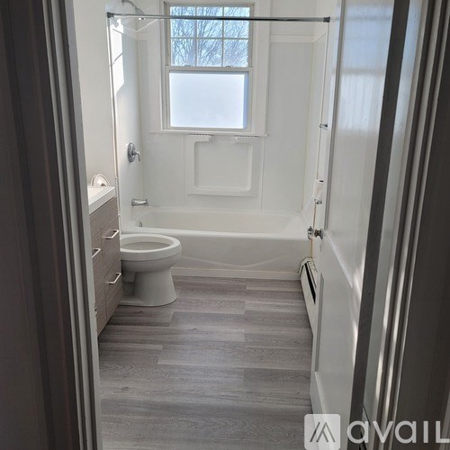 A bathroom with a toilet, tub, and window.