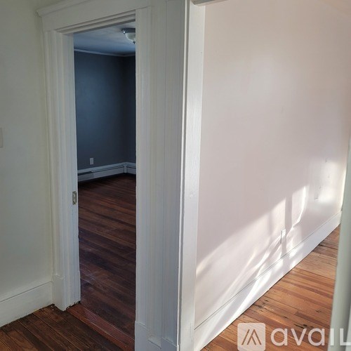 A room with a white door and wooden floor.