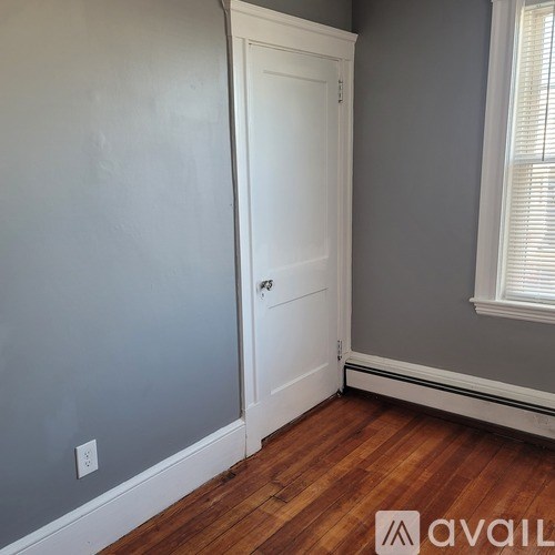 A white door is in a room with wooden floors and grey walls.