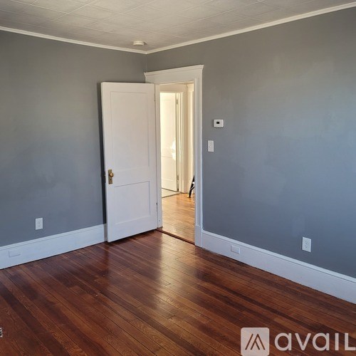 A room with a white door and wooden floor.