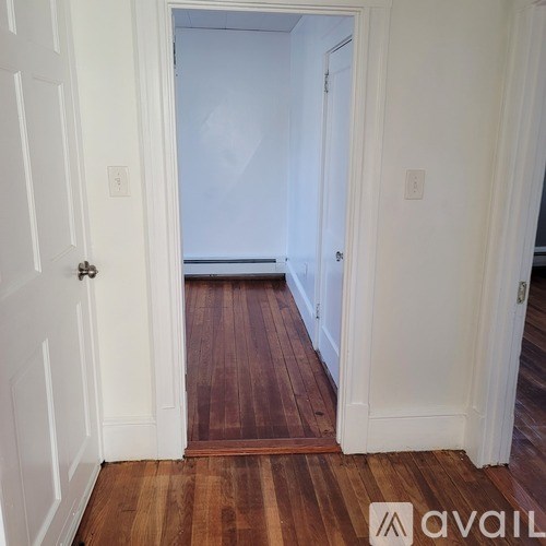 A hallway with wood floors and white walls.