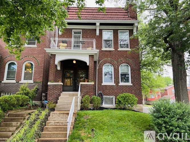 A red brick house with a white balcony and a black door.
