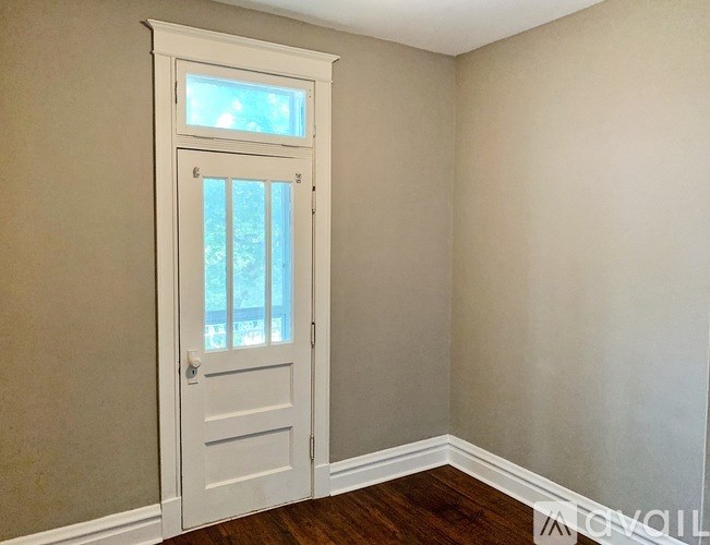 A white door with a window is in a room with a wooden floor.