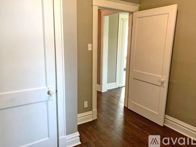 A hallway with a white door on the left and a white door on the right.