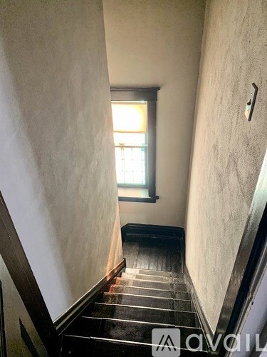 A narrow hallway with a window and a door on the right.