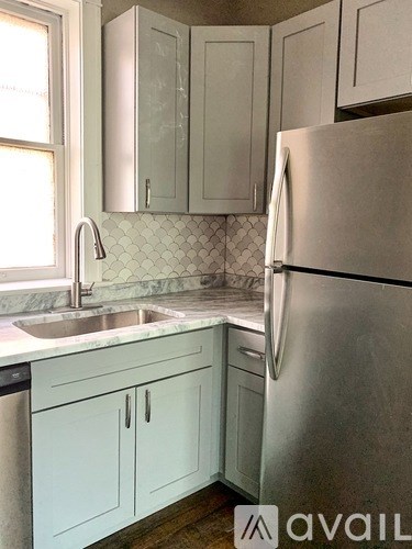A kitchen with a stainless steel refrigerator and white cabinets.
