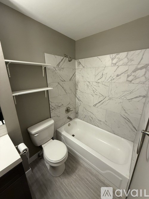 A white toilet sits in a bathroom next to a sink and a bathtub.