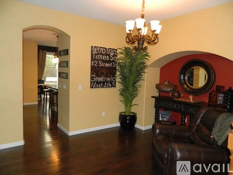 A living room with a brown leather couch and a chandelier.
