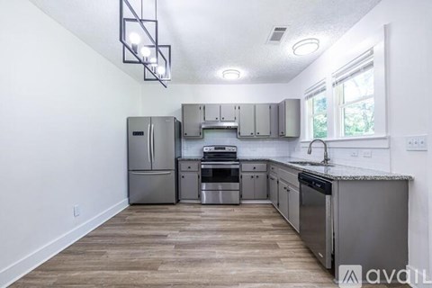 A kitchen with stainless steel appliances and wooden flooring.